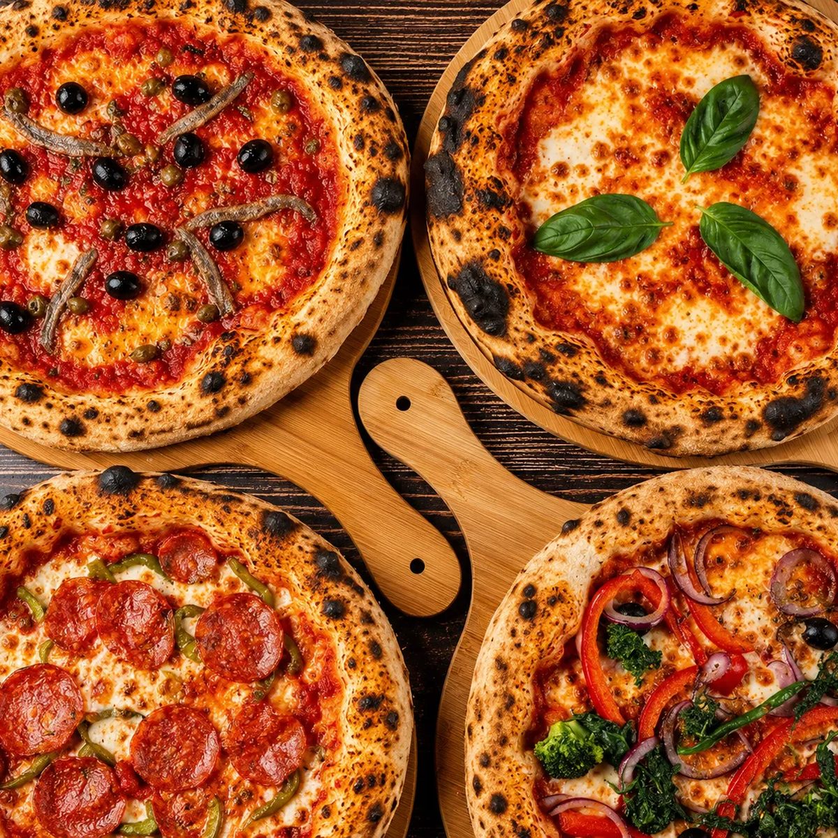 Vier Pizzen auf Holzbrettern